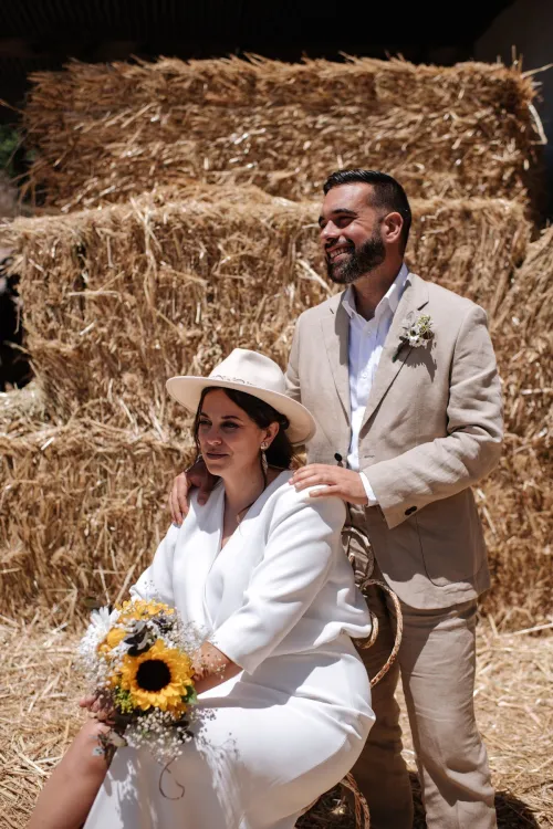 Los novios vestidos de blanco junto a pacas de heno